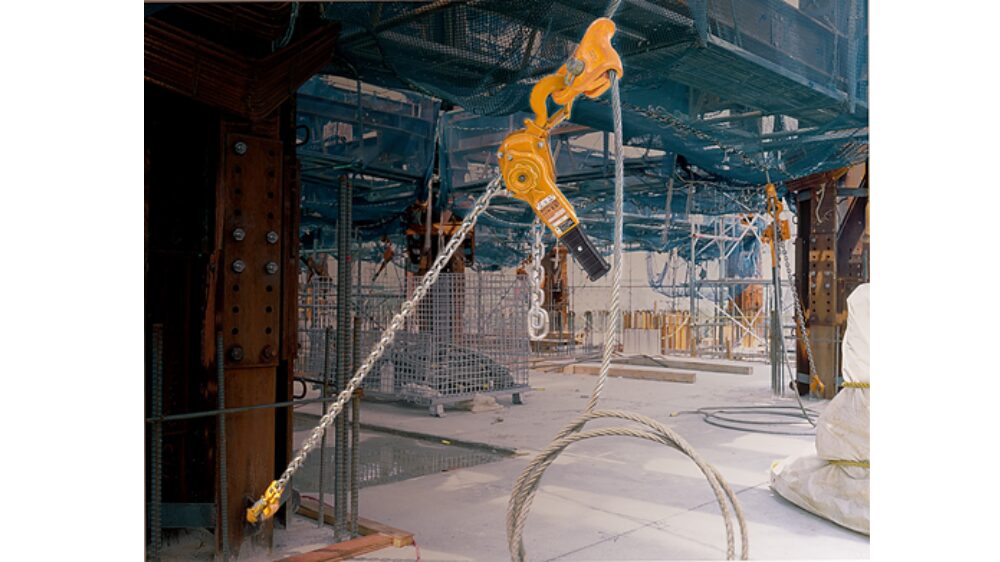 Industrial hoist and cables used in construction site scaffolding, displaying heavy lifting equipment and metal framework.