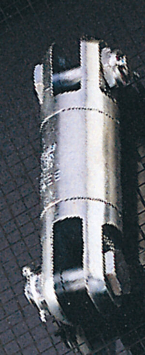 Close-up of a metal industrial component with bolts on a grid-patterned surface.